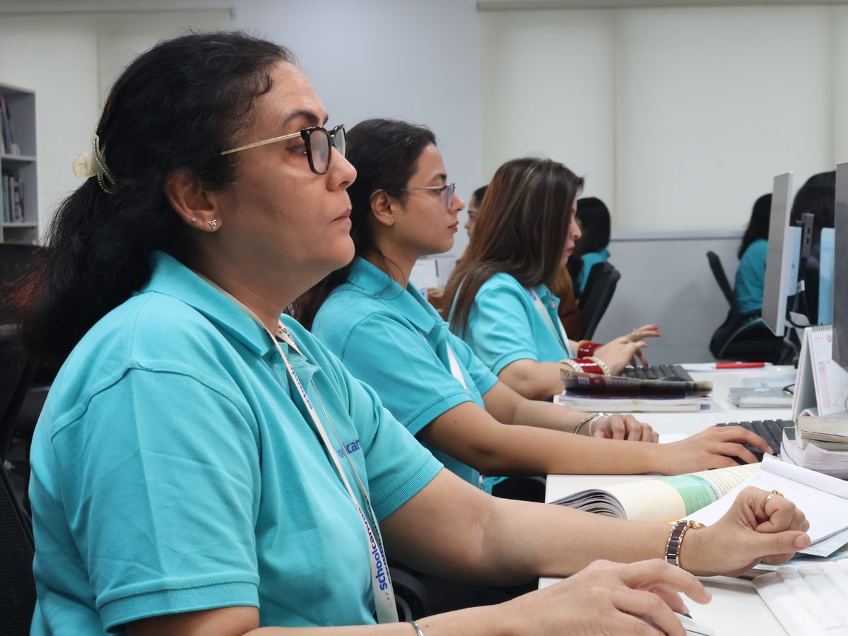 Assist content team members writing and checking lessons at their computers, with textbooks open beside them