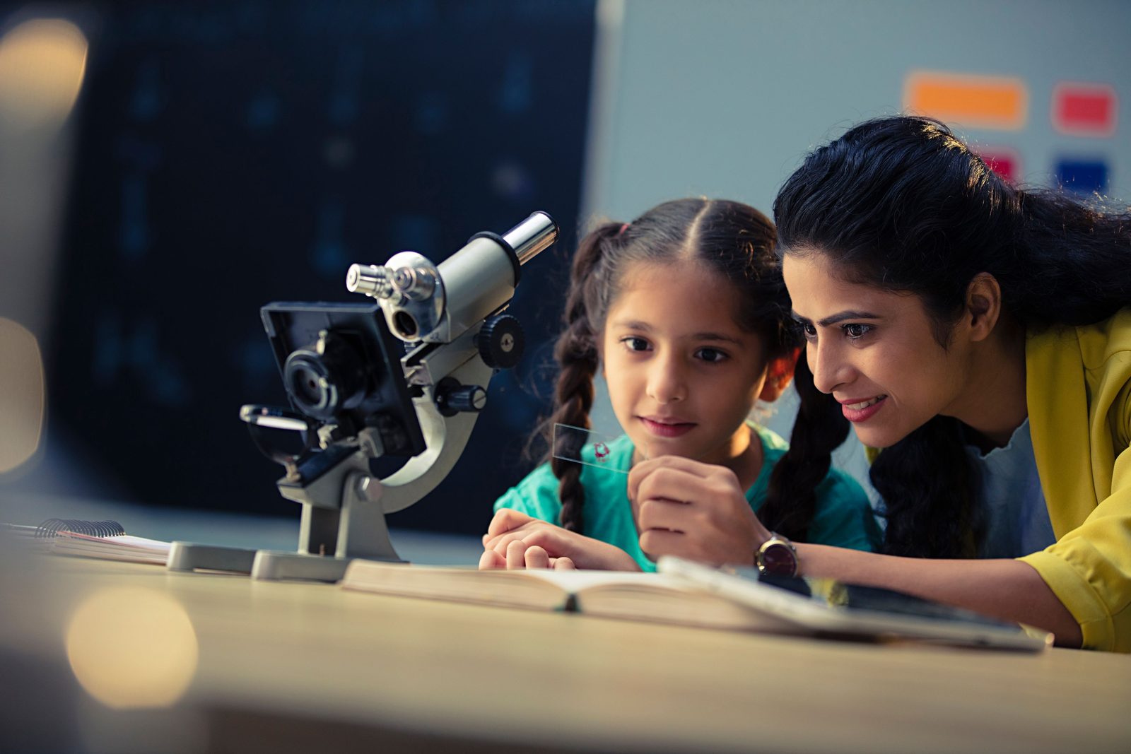 A teacher helping a young student look through a microscope, the kind of activity an HPC records