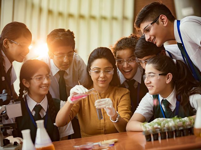 Senior students and their teacher in a chemistry lab, learning up to Class 12
