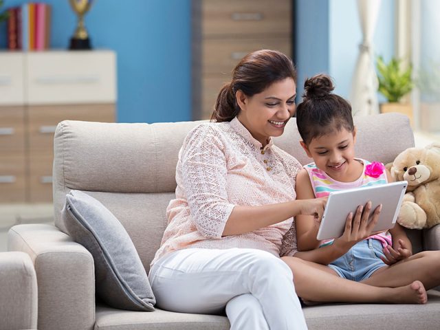 A young girl learning on a tablet with her mother, from Class 3 onwards