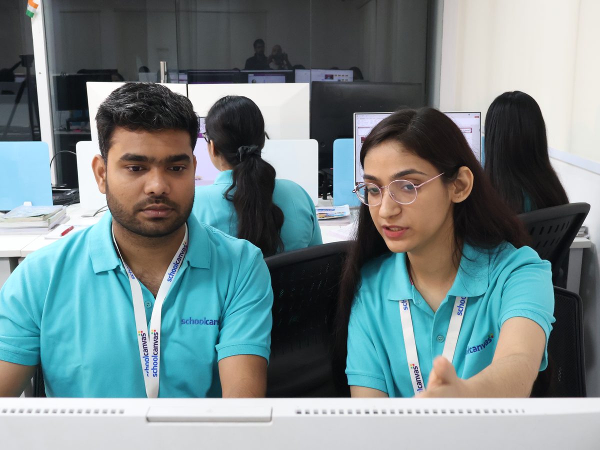 Two staff members working side by side at their computers in an office