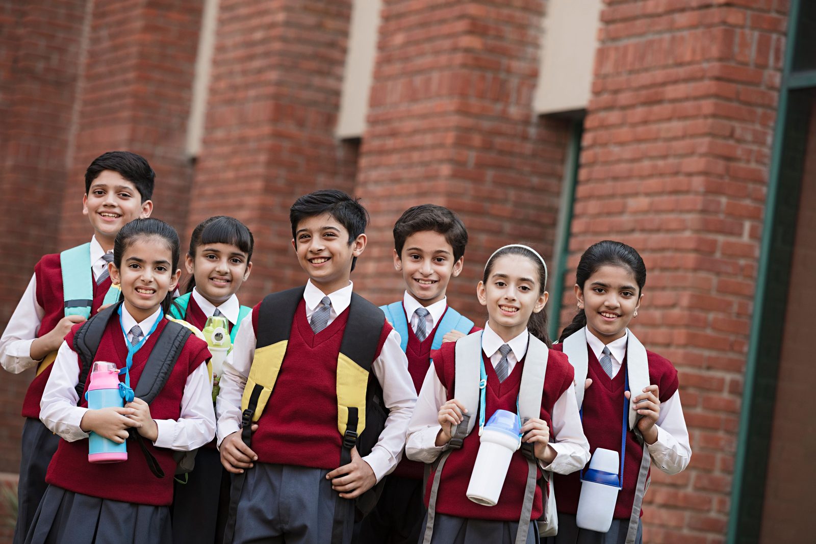 A smiling group of students in school uniform outside their school