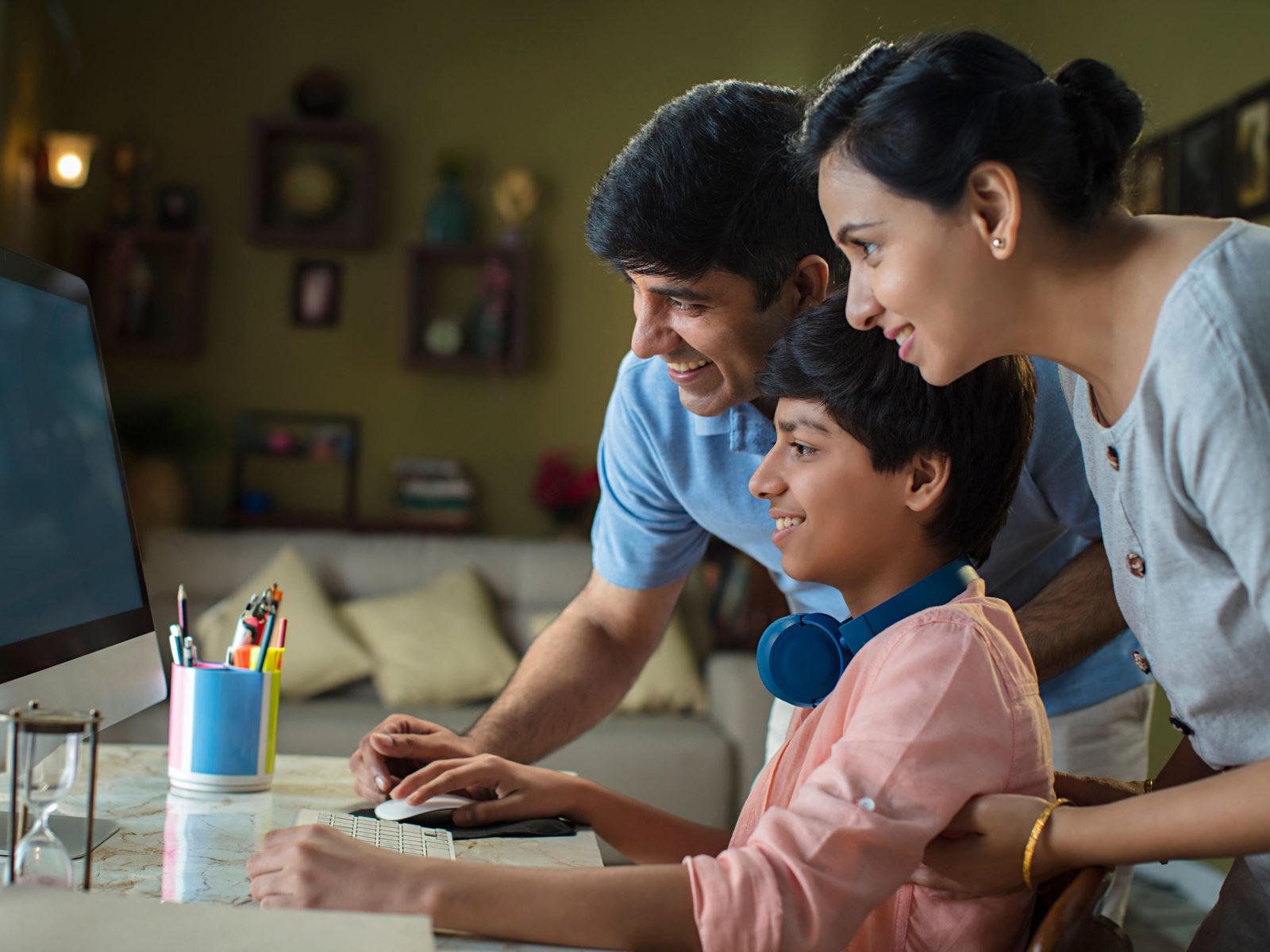 Parents looking over their son’s shoulder at the computer at home