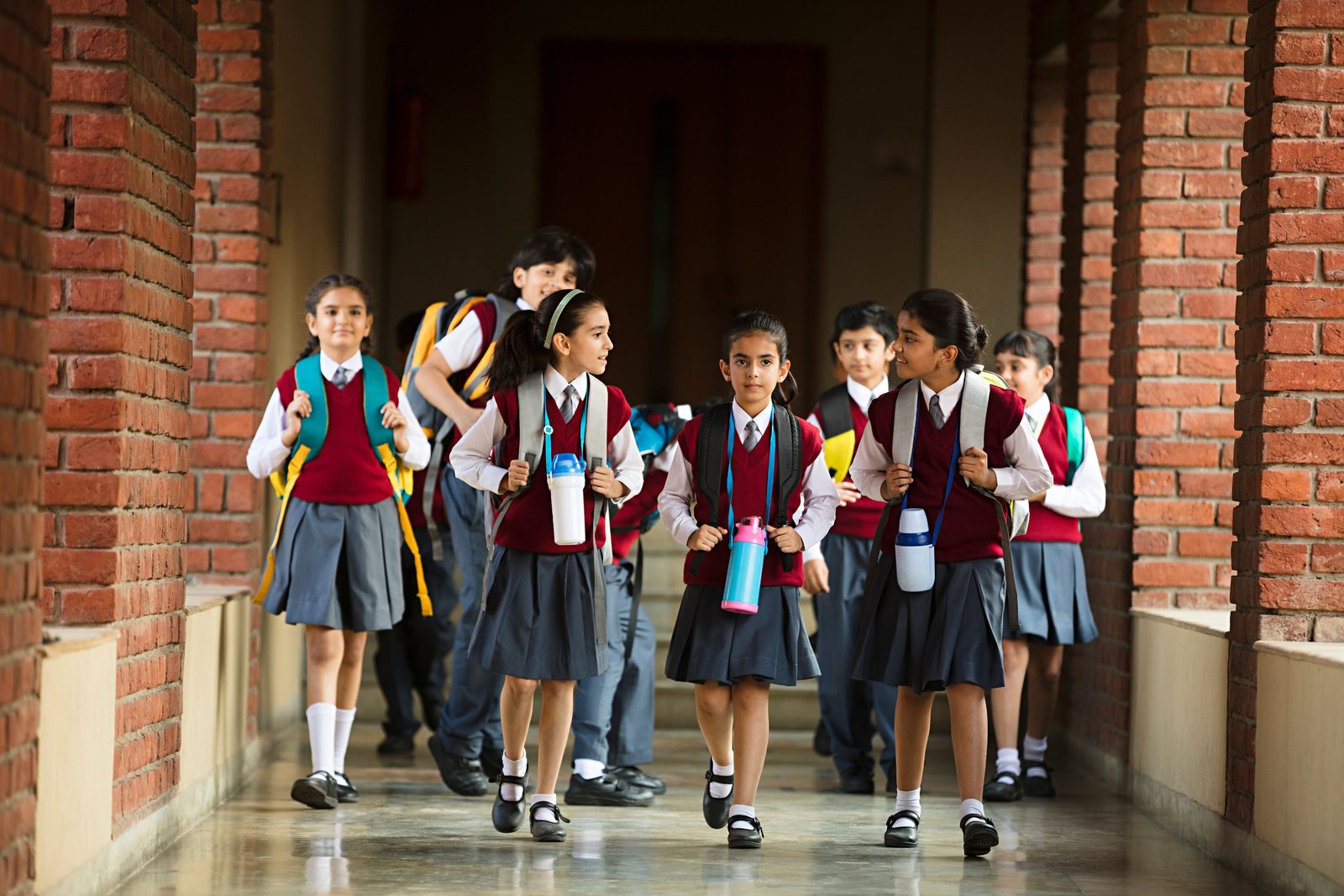 Students with school bags walking down the school corridor, safe inside the gate during the school day